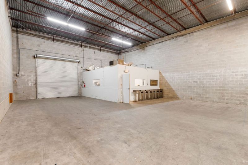 Open warehouse bay inside 1030 SE 4th Street with concrete block walls, a roll-up door, and an interior office build-out