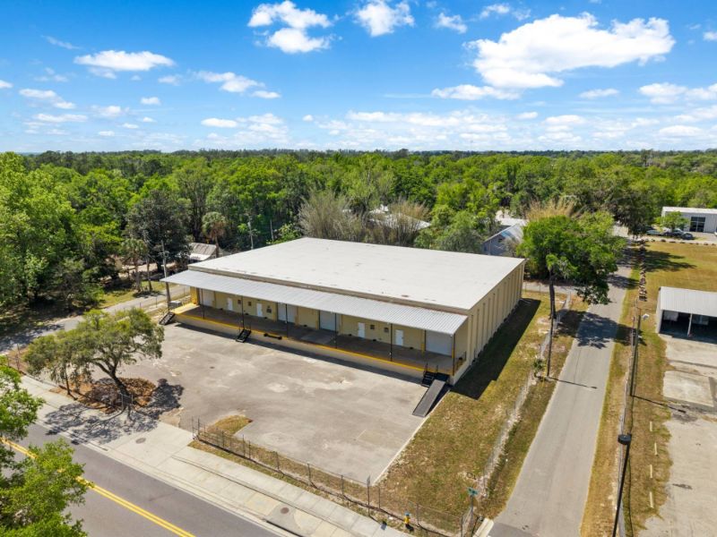 Aerial view from the street corner of the warehouse at 1030 SE 4th Street showing the covered dock, gated fence, and truck yard