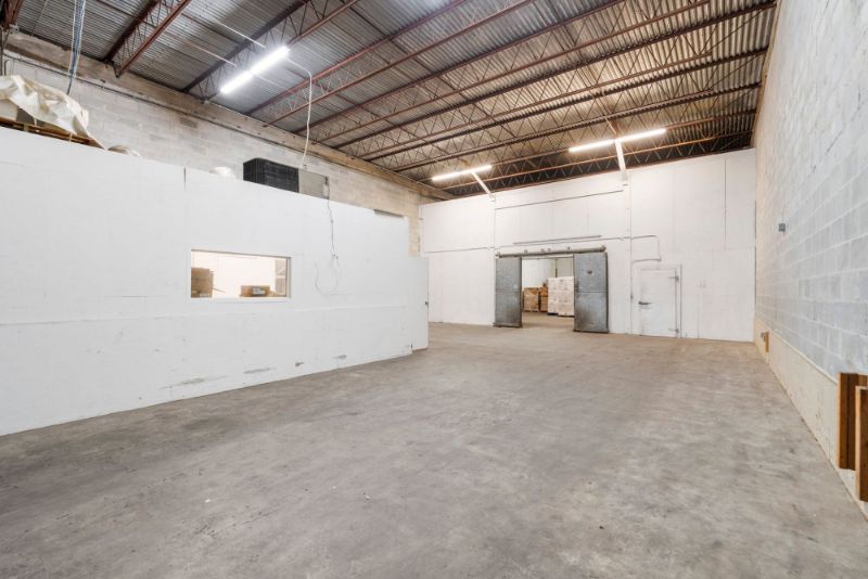 Open warehouse bay at 1030 SE 4th Street with high clear-span ceilings and an interior office wall with window