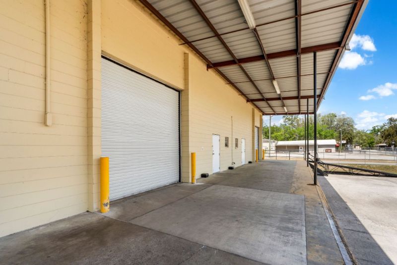 Close view of a roll-up door with yellow safety bollards under the covered loading dock canopy at 1030 SE 4th Street
